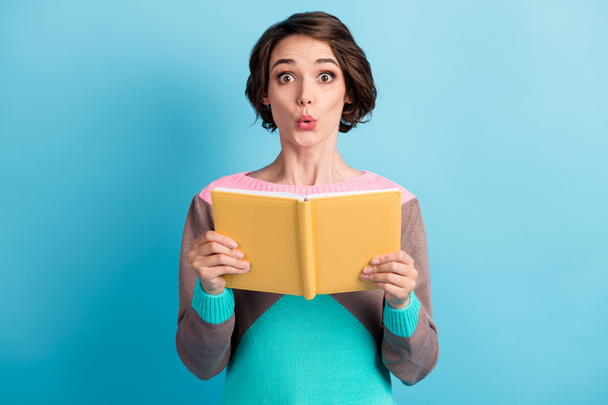 Photo portrait of shocked impressed female student holding yellow book isolated on vivid blue color background - Foto, immagini