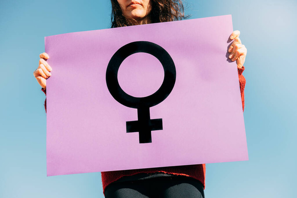 γυναίκα που κρατά ένα μωβ φεμινιστικό λάβαρο με το σύμβολο των γυναικών. φεμινιστική έννοια - Φωτογραφία, εικόνα