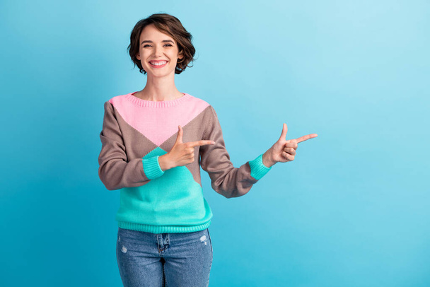 Photo portrait of happy woman pointing two fingers at blank space smiling isolated on pastel light blue colored background - Foto, Imagem