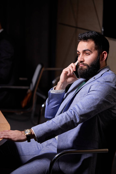 handsome arabic male sits listening to colleagues speech - 写真・画像