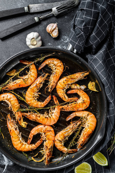 Grilled giant prawns, shrimps with garlic, lemon, spices in pan. Black background. Top view - Foto, imagen