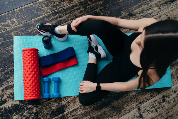 Stretching coach is on yoga mat with sports rubber bands and massage roller - Foto, Imagem