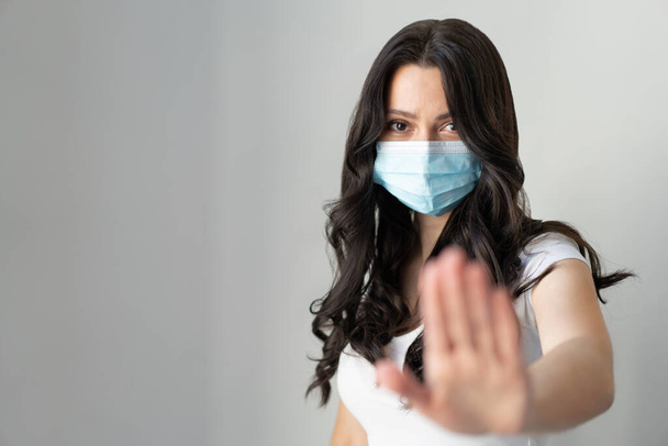 Frau trägt Maske zum Schutz vor Krankheiten und zeigt Stop-Hands-Geste zum Stopp des Coronavirus-Ausbruchs. Aufruf, zu Hause zu bleiben. Coronavirus-Konzept. - Foto, Bild