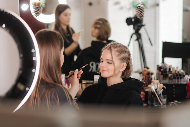 Donna make make up per attraente donna capelli biondi in studio. Video di truccatore che applica cosmetici per bel modello - Foto, immagini