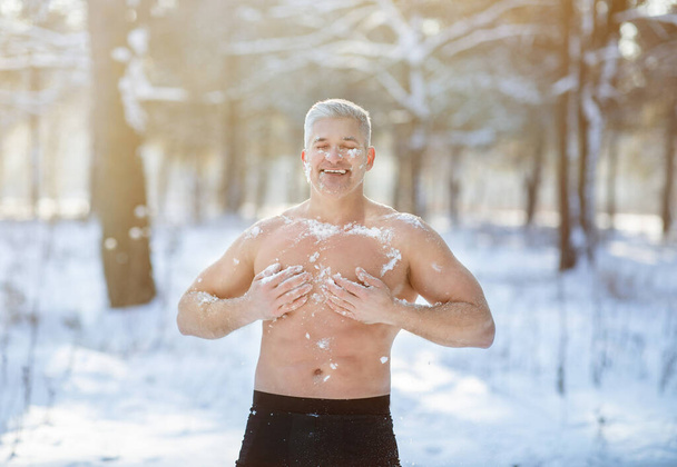 Concetto di formazione all'esposizione al freddo. Ragazzo anziano allegro temperare il suo corpo con la neve nella foresta invernale gelida - Foto, immagini