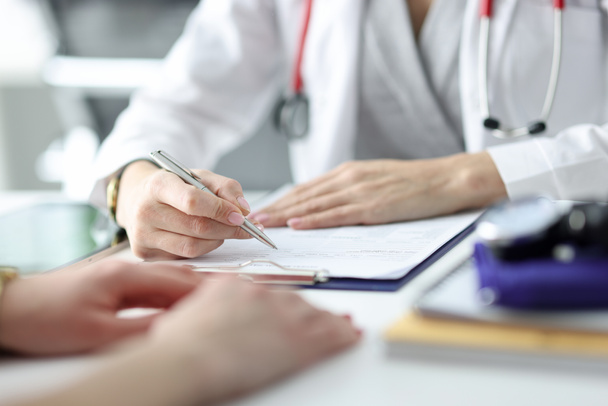 Médico aconselhando paciente e escrevendo em documentos close-up - Foto, Imagem