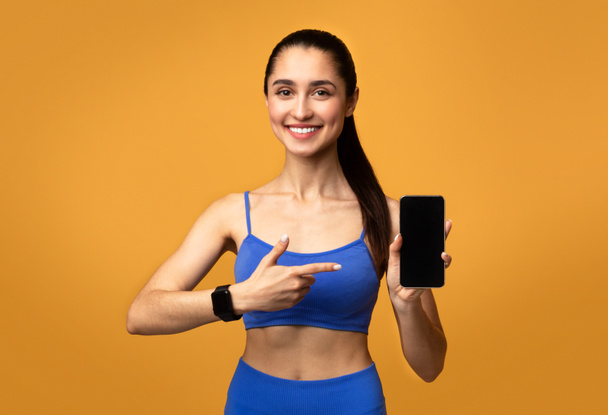 Happy sporty woman showing phone with blank screen - 写真・画像