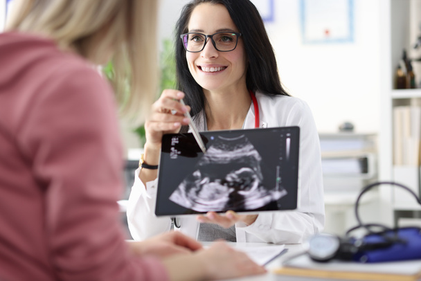 Ginecólogo mostrando paciente ultrasonido de feto en tableta - Foto, imagen