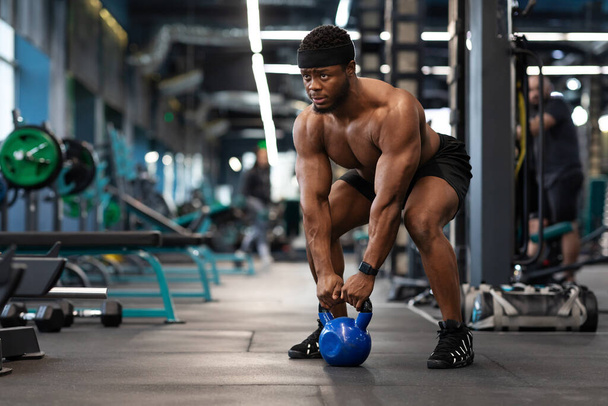 Muscular shirtless bodybuilder exercising with kettlebell at gym - Photo, Image