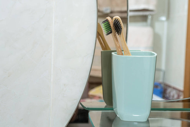 2 cepillos de dientes en el baño con una taza en el fondo del espejo. - Foto, imagen