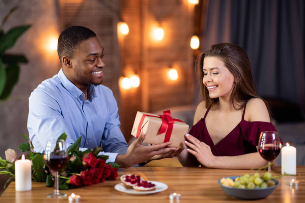Caring schwarz kerl überraschend freundin mit geschenk auf romantisch datum im restaurant - Foto, Bild