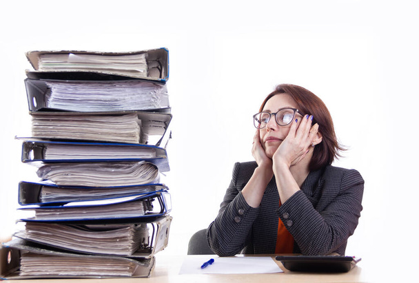 girl in glasses stands about a huge stack of work folders with papers holding her head - Photo, Image