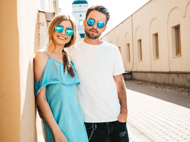 Portrait of smiling beautiful woman and her handsome boyfriend. Woman in casual summer jeans dress. Happy cheerful family. Female having fun. Couple posing on the street background in sunglasses - 写真・画像