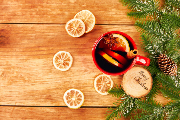 A glass of mulled wine with lemons, cinnamon, and star anise, and Christmas decorations - Photo, Image