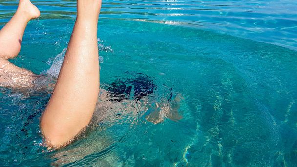 Young female swimming and diving in crystal clear turquoise water. Sea, summer, vacation, sunny day, fun, healthy. - Fotografie, Obrázek