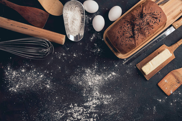 An overhead shot of bread on a black table with ingredients on the side - Fotoğraf, Görsel