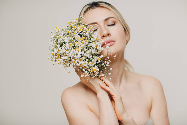 Young and beautiful blonde woman with daisies bouquet - Photo, Image