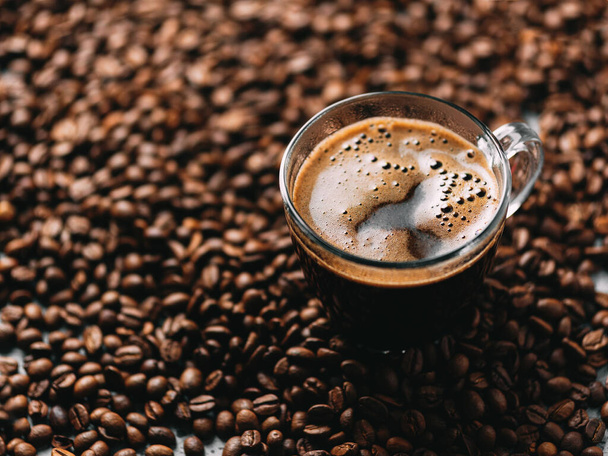 Скляна чашка кави еспресо стоїть на кавових зернах крупним планом
 - Фото, зображення