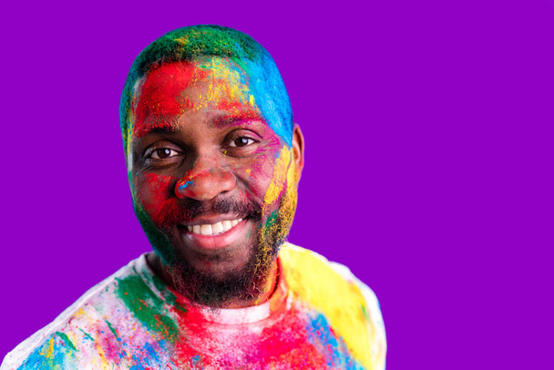 Afro american man celebrate holi festival in violet studio background - Foto, immagini
