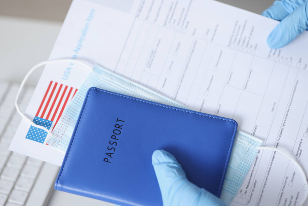 Hände in Gummihandschuhen halten Pass und Dokumente für US-Visa in der Nähe - Foto, Bild
