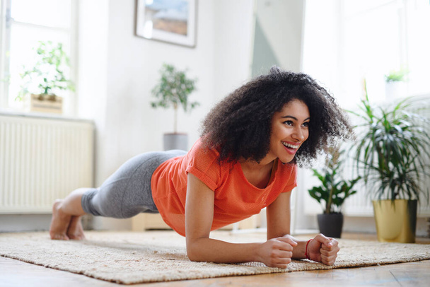 Young woman indoors at home, doing exercise. Sport concept. - Photo, Image