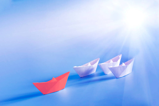Group of origami boats on blue background. Red paper ship leading. Leadership, Business for innovative solution concept - Photo, Image
