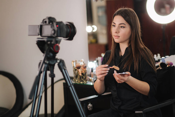 Beroep make-up kunstenaar vrouw beoordelen schoonheidsproducten op een video blog in beauty studio. Vrouw met ringlamp - Foto, afbeelding