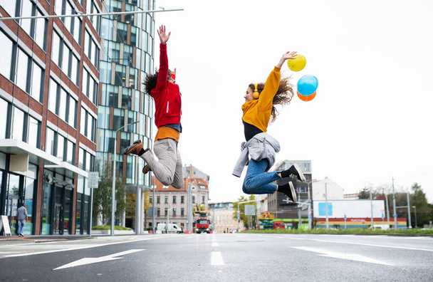 Young couple with balloons jumping outdoors on street, video for social media concept. - Foto, Imagen