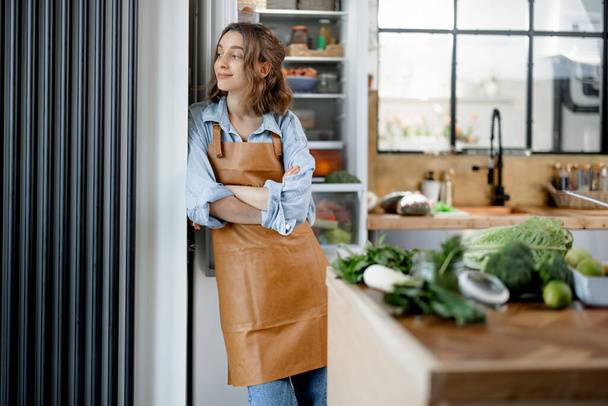 Женщина, останавливающаяся в красивой внутренней кухне  - Фото, изображение