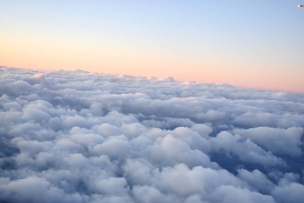  Mavi gökyüzünde, gün batımında yüzen beyaz bulutların güzel turuncu rengi. Uçak penceresinden bakıldığında. - Fotoğraf, Görsel