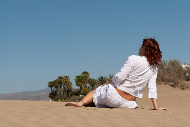 woman dressed in white relaxed on sand dunes - Valokuva, kuva