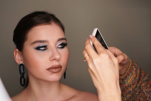 Make up artist taking mobile photo for the model with makeup - Foto, imagen