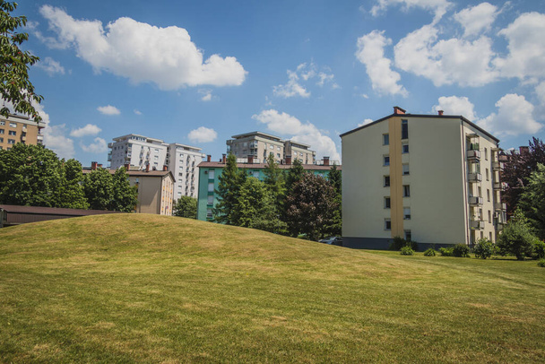 Facades of a decently renovated socialistic type city blocks. Fresh walls and paint on a city neighbourghood make it almost brand new. Green hill for kids playground in the foreground - Zdjęcie, obraz
