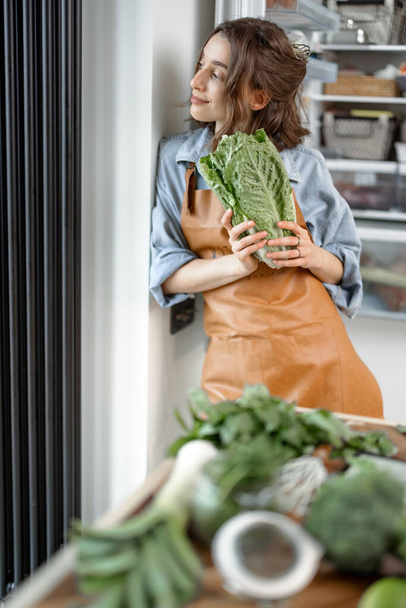 Woman with roman salad on the kitchen - 写真・画像