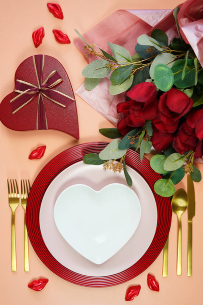 Обеденный стол Валентина с красными розами, подарками и макетом шоколада. - Фото, изображение