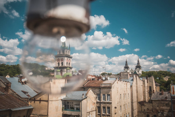 View of the Dominican Cathedral and Assumption church and its belltower in Lviv, Ukraine on a sunny day with some clouds. light bulb in the foreground, Lvov Cityscape - Фото, изображение