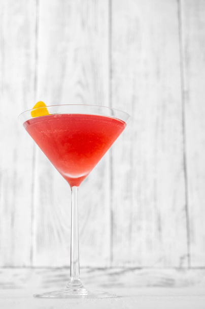 Glass of Cosmopolitan cocktail garnished with a lemon zest - Foto, Bild
