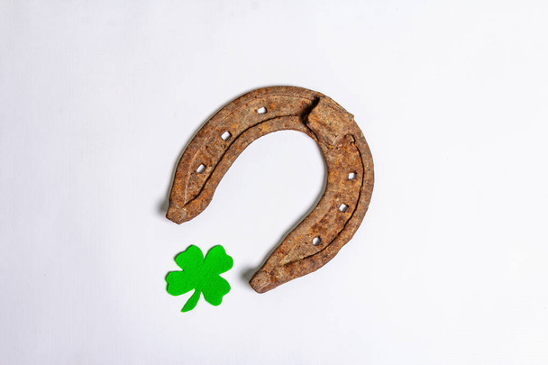 Badly worn horseshoes with a felt clover leaf isolated on white background. Good luck symbol, St.Patrick's day concept - Photo, Image