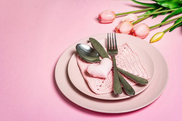 Romantische eettafel. Liefdesconcept voor Valentijnsdag of moederdag, huwelijksbestek. Minimalistische stijl, rozenborden, een boeket van tulp, Haak servet, plaats voor tekst - Foto, afbeelding