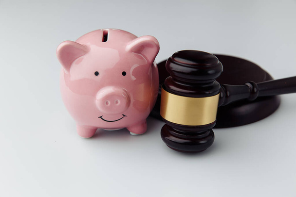 Judge gavel and pink piggy bank on a white desk close-up. Loan and finance concept - Zdjęcie, obraz