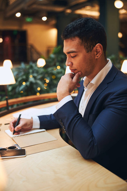 Handsome dark-haired businessman taking notes on paper - Φωτογραφία, εικόνα