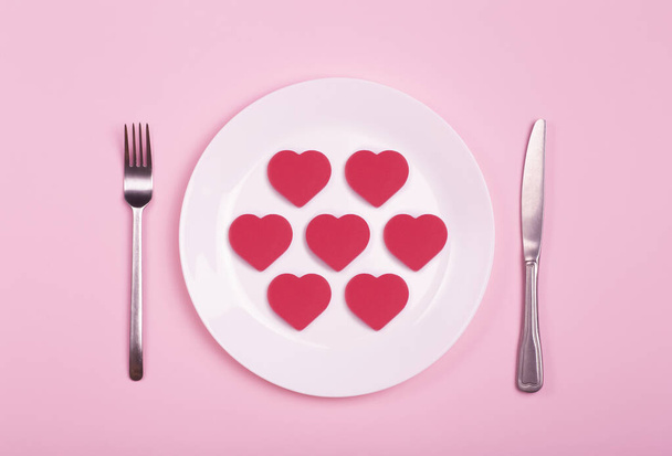 Coração em um prato vazio em um fundo rosa. Conceito criativo de arte mínima. Coração vermelho como um símbolo de amor, romance e ideia "like" - Foto, Imagem