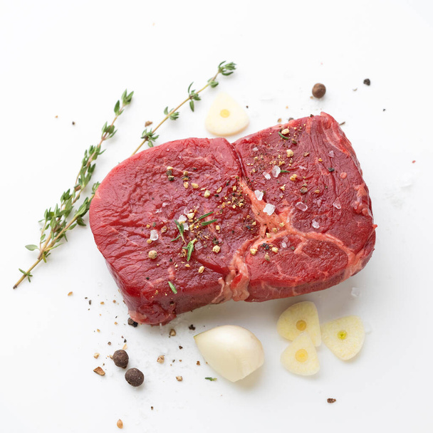 新鮮な生牛のステーキ肉とスパイスの白を背景にトップビュー - 写真・画像