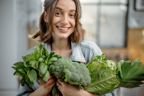 Woman with fresh green vegetables on the kitchen - Fotografie, Obrázek