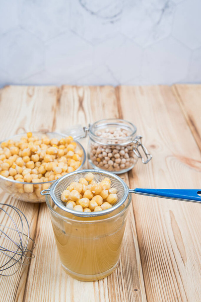 On a light wooden background, a decoction of Aquafaba chickpeas. Aquafaba is a source of vegetable protein. - Photo, Image