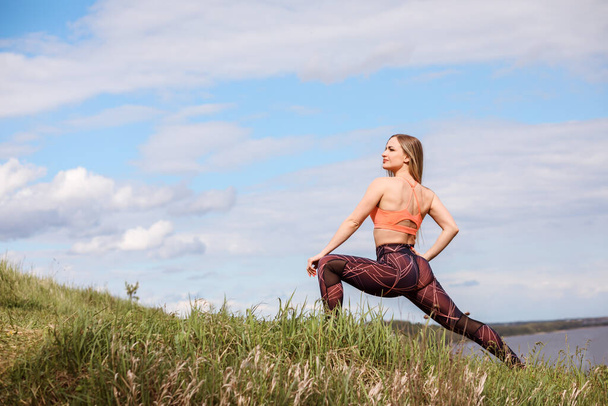 Athletic woman is doing lunge, working out outdoors by the nature. - Photo, Image