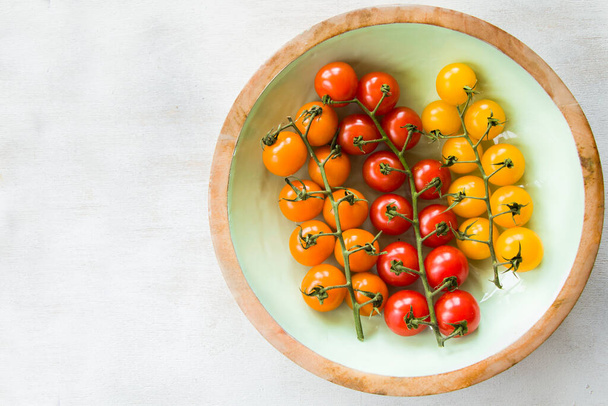 Todos los colores y coloridos tomates cherry, vista de alto ángulo del fondo de los alimentos, colores rojo, amarillo y naranja - Foto, imagen