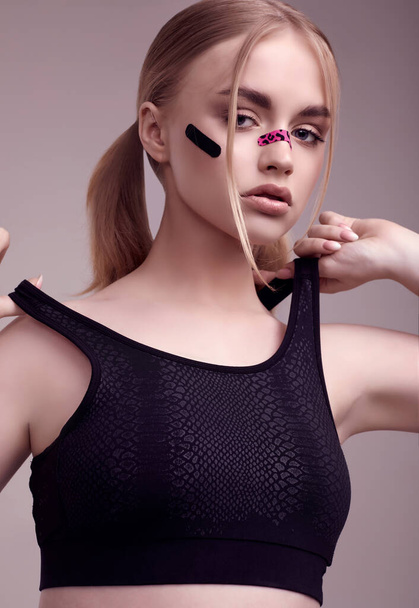 Sensual portrait of beautiful blonde girl with glamour plasters on her face posing at studio background - Foto, afbeelding