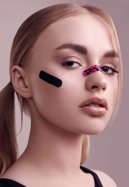 Sensual portrait of beautiful blonde girl with glamour plasters on her face posing at studio background - Fotoğraf, Görsel