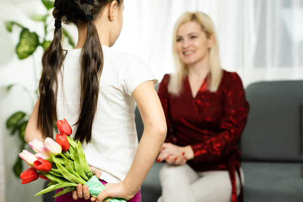 Boldog anyák napját. Gyermek lánya gratulál anyának, és ad neki egy képeslapot és virágokat tulipán - Fotó, kép
